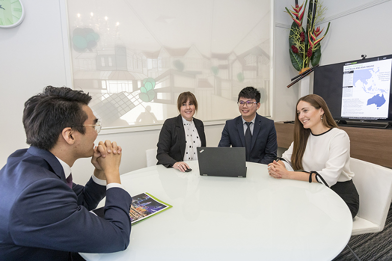 Three corporate team members photographed talking to a prospective client